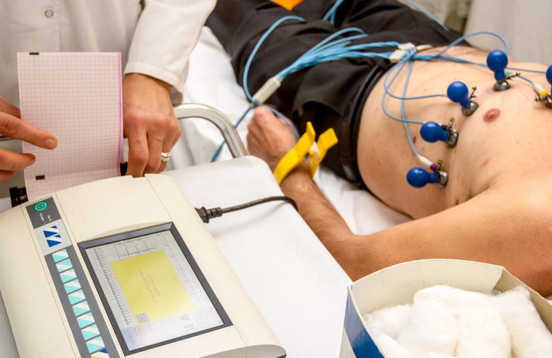 A healthcare technician monitors a male patient who is hooked up to an electrocardiogram machine.